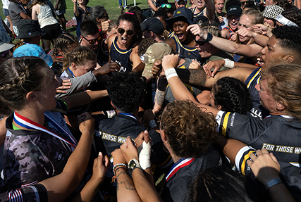 Wearing a pink ribbon in her hair, Navy Ensign Megan Neyen leads a huddle of rugby players from all services in a cheer ‘For Those Who Can’t’ at the conclusion of the 2024 Armed Forces Women’s Rugby Championships in San Diego, Calif. July 13, 2024. Team Army wore the motto “For Those Who Can’t’ on their uniforms to honor injured or deceased female service members. (DoD photo by EJ Hersom)